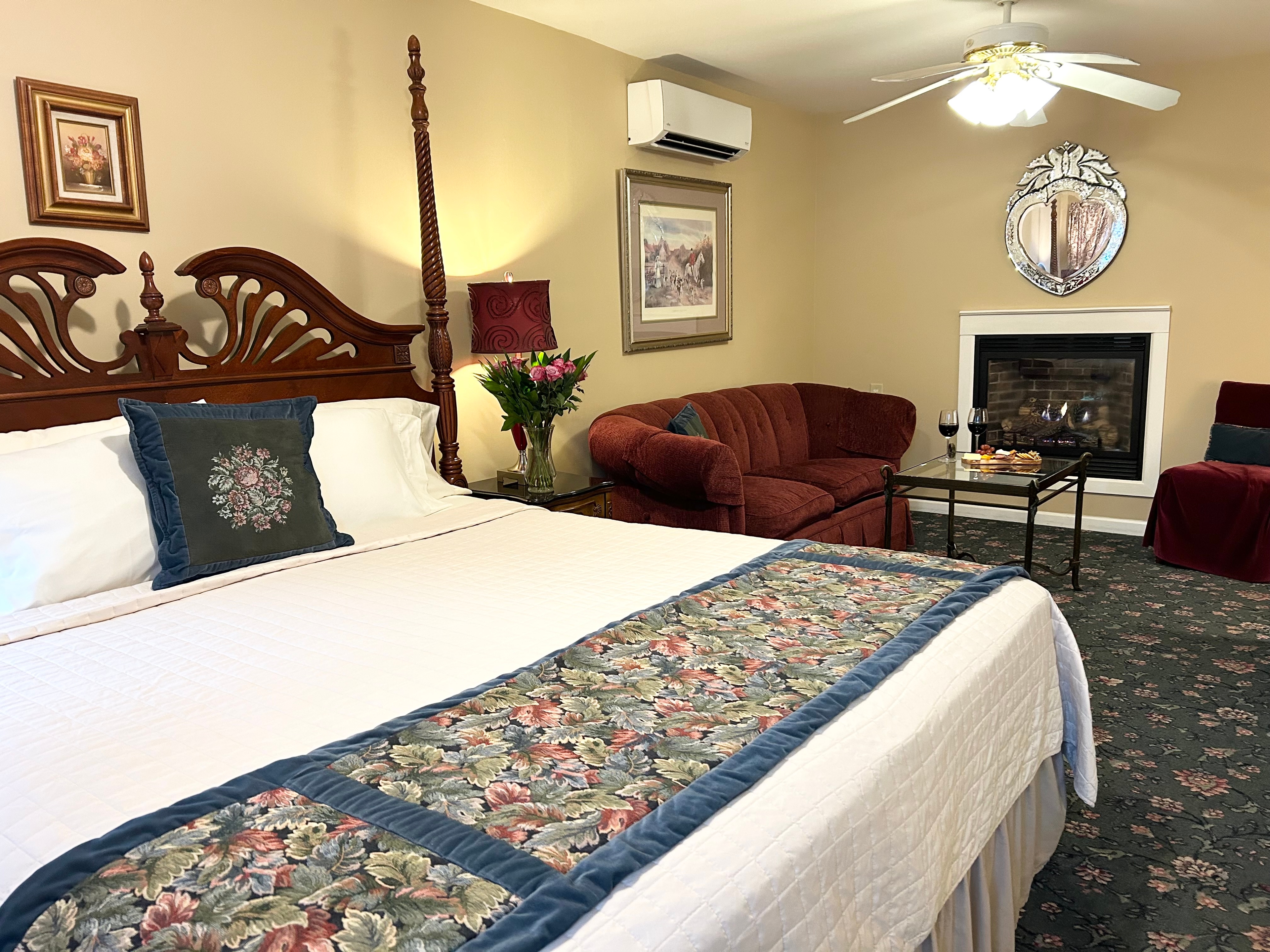 Side view of king bed with couch and table in front of the gas fireplace