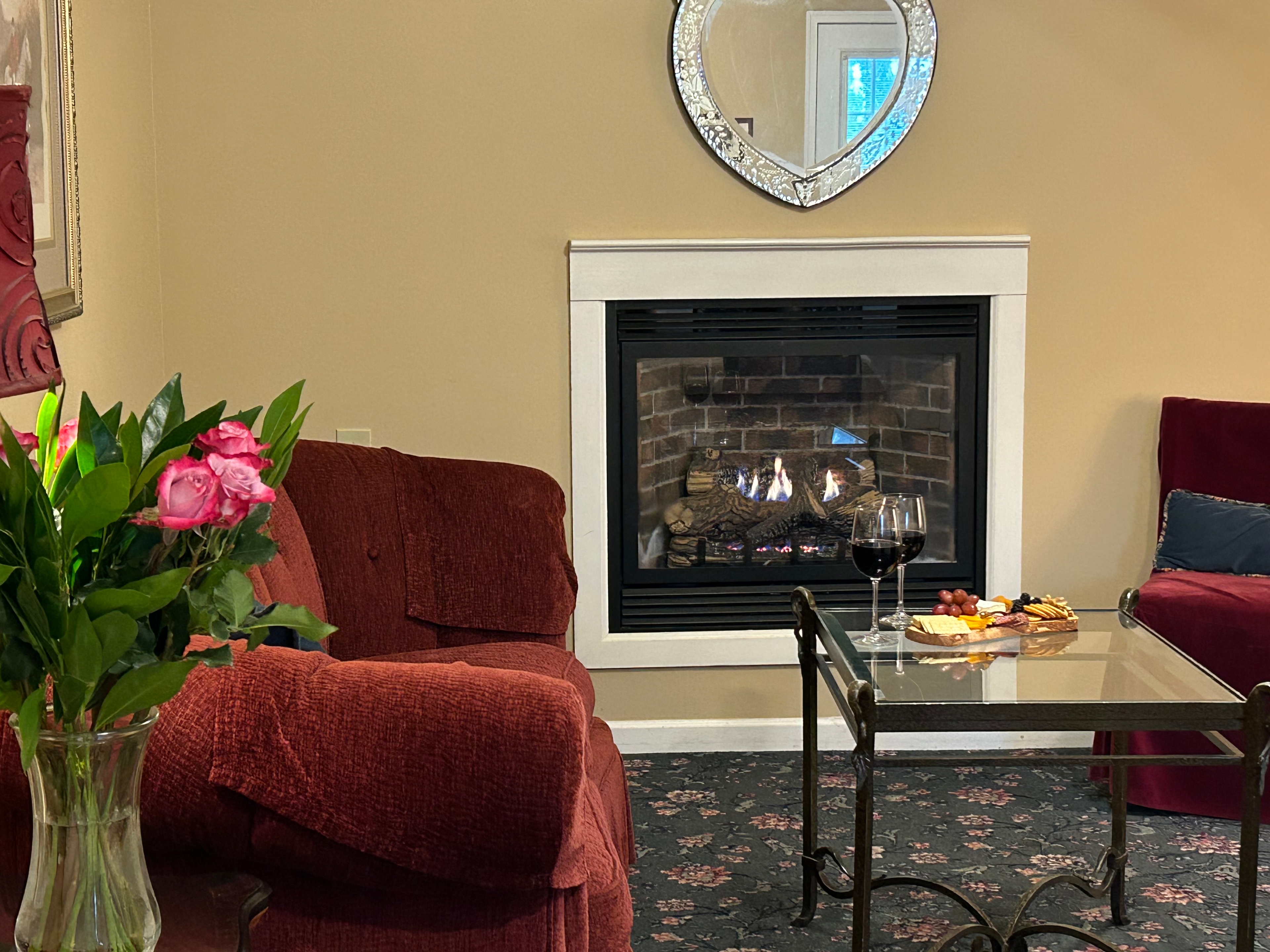 Flowers in foreground of sitting area with couch, table and gas fireplace