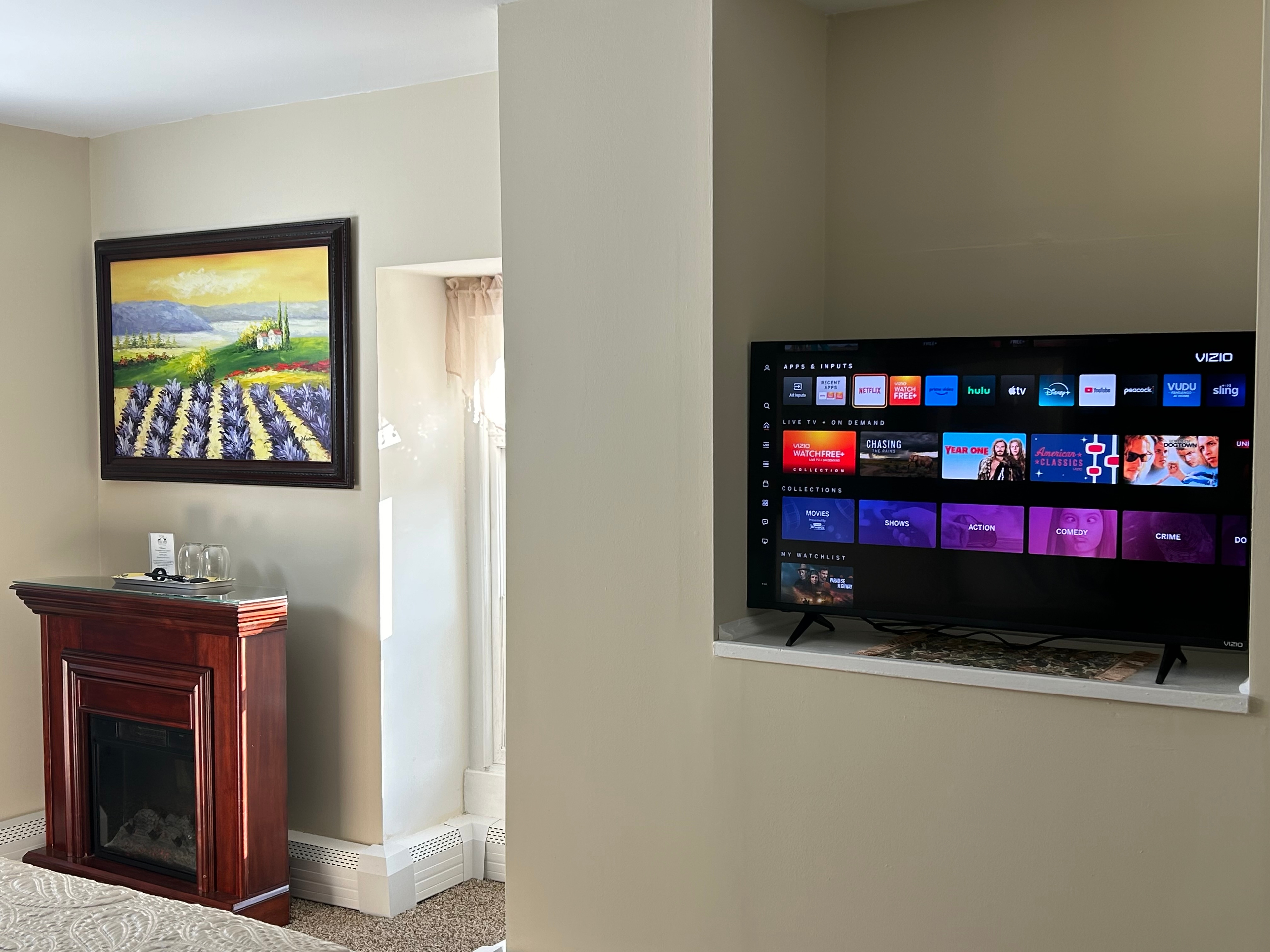 TV showing Netflix avalable and a nice painting of a lavender  field above a fireplace