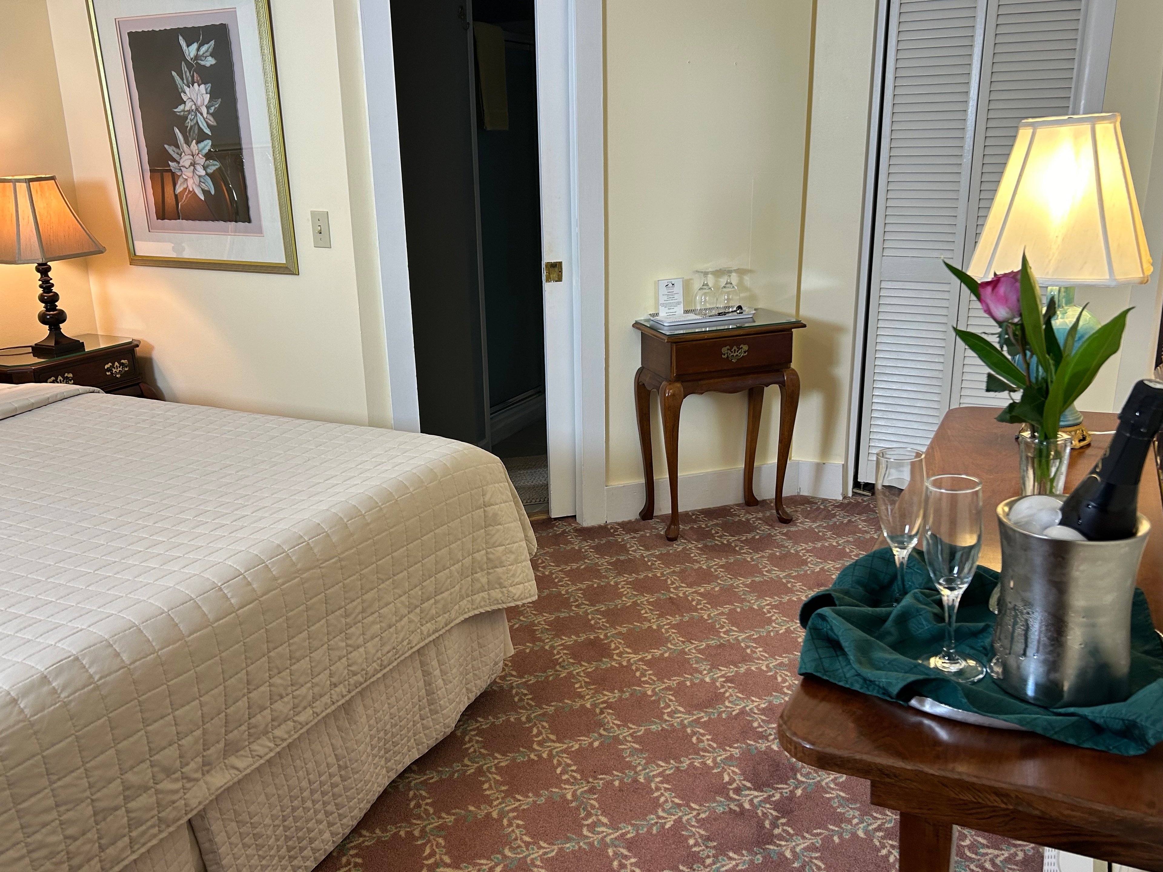 King size bed with flower bouquets on the desk and bathroom is visible