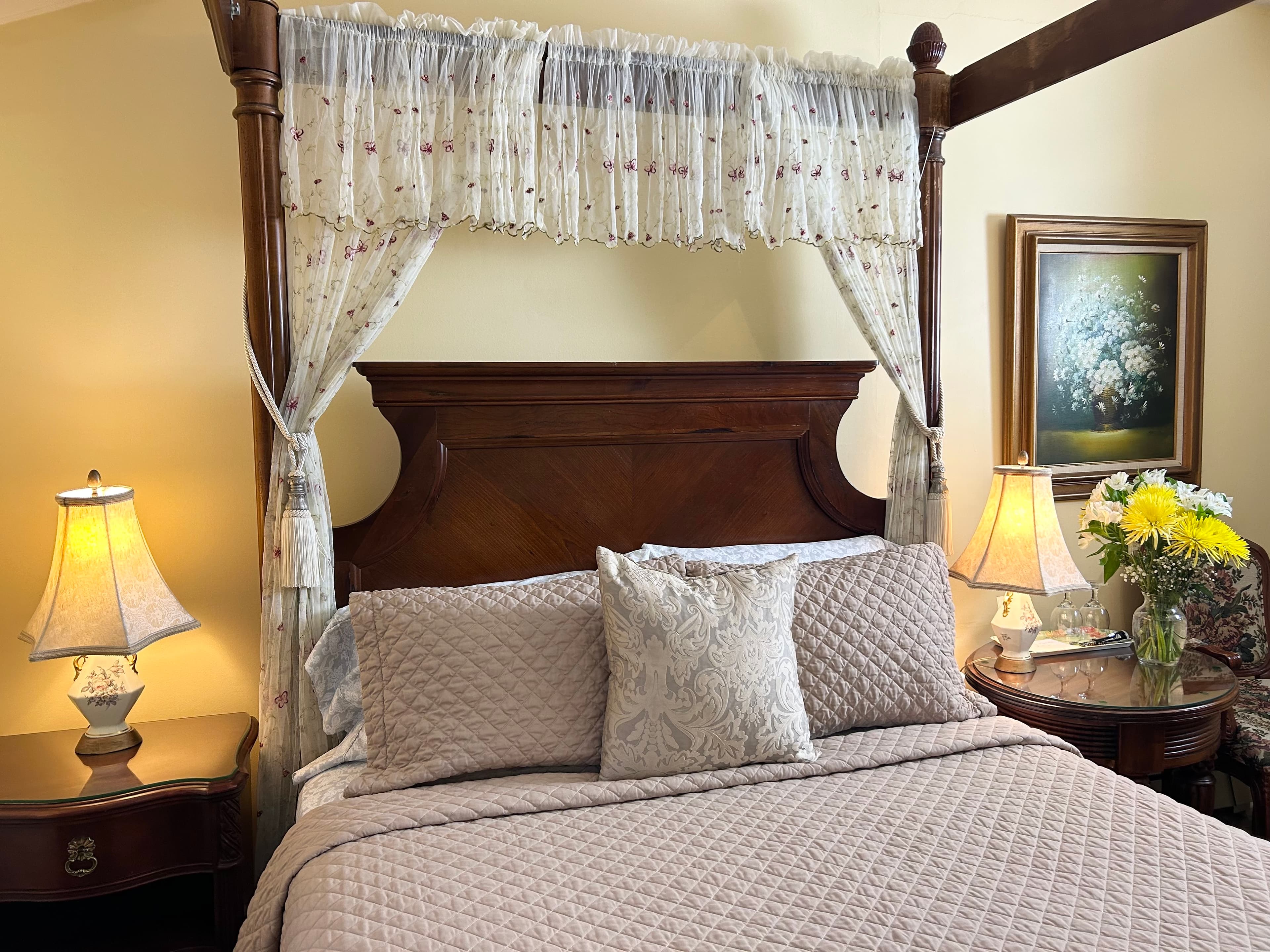 "Front view of four poster walnut queen size bed with two side tables and two lamps"