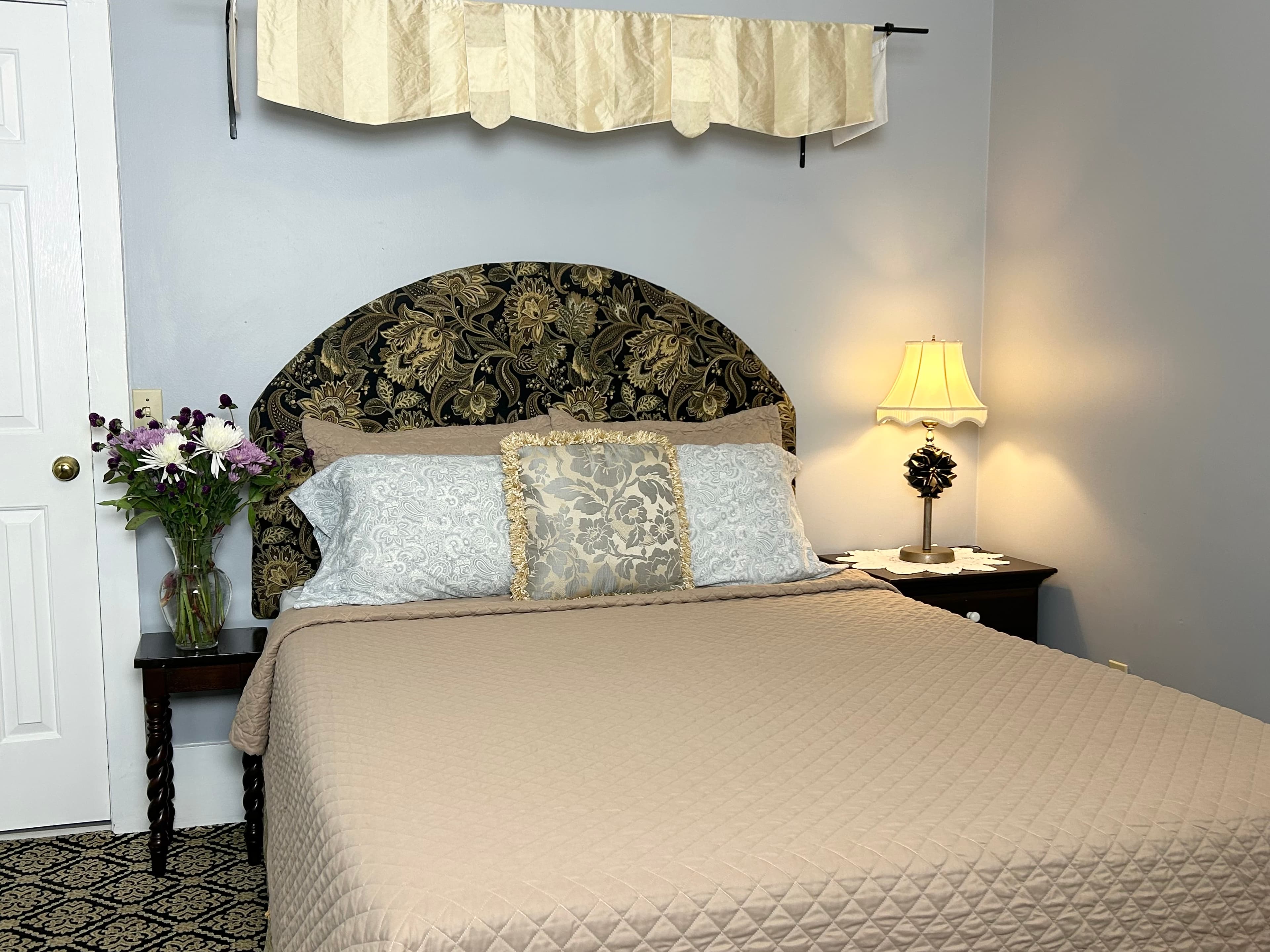 Queen bed with 2 nightstands, flowers and a lamp