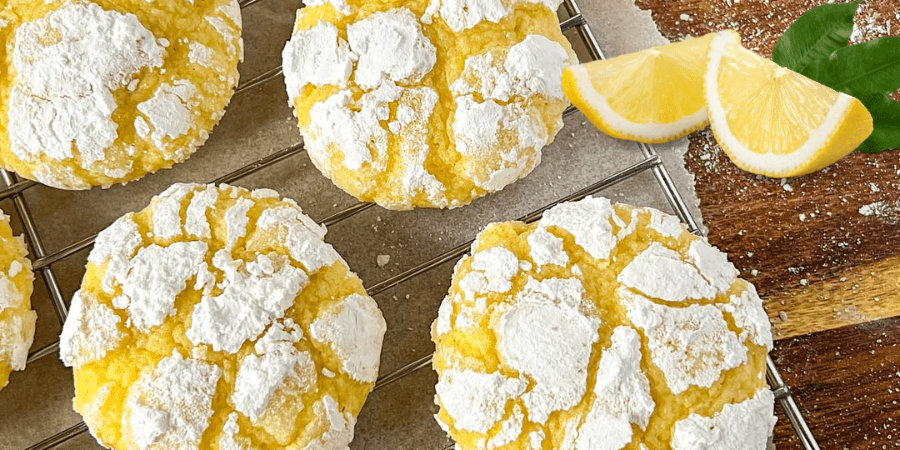 Pineapple lemon crinkle cookies dusted with powdered sugar on a cooling rack. Pineapple lemon crinkle cookies dusted with powdered sugar on a cooling rack.